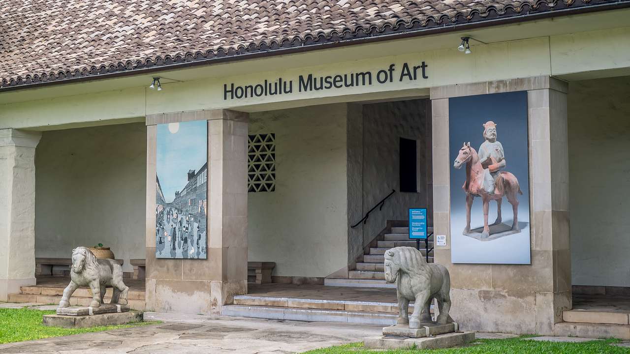 A building with a Honolulu Museum of Art sign and sculptures in front of it