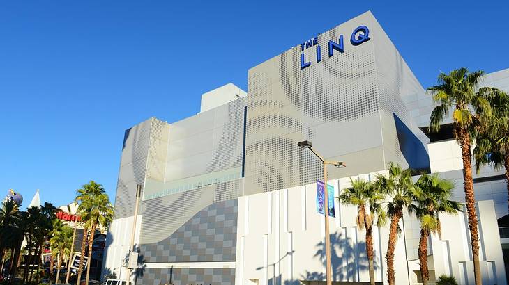 A contemporary hotel building with LINQ sign and palm trees in front of it