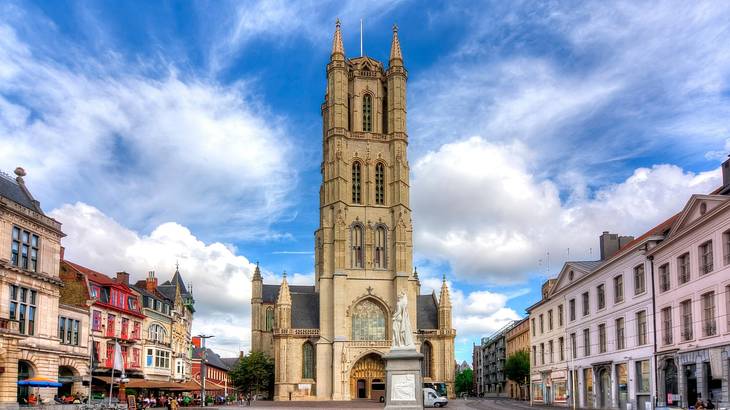A tall Gothic church tower in the centre of a colourful city square