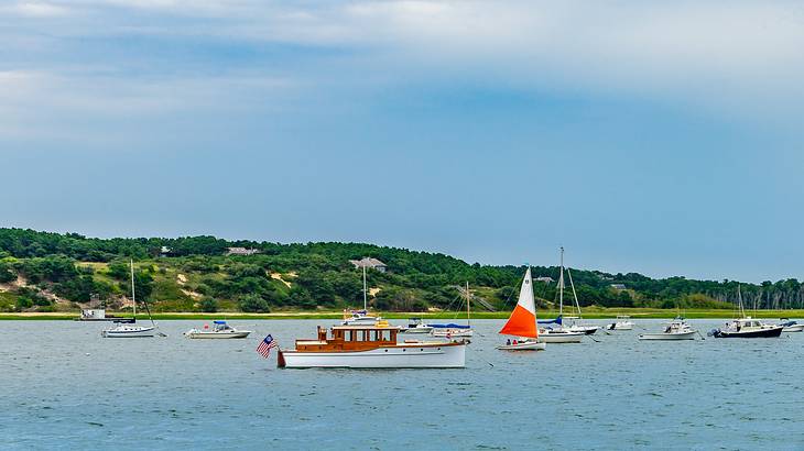 Boats on the water with green hills in the background under a blue sky