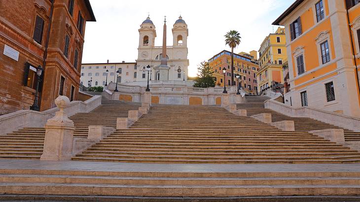 Stairway surrounded by brightly coloured buildings leading to an obelisk and a church