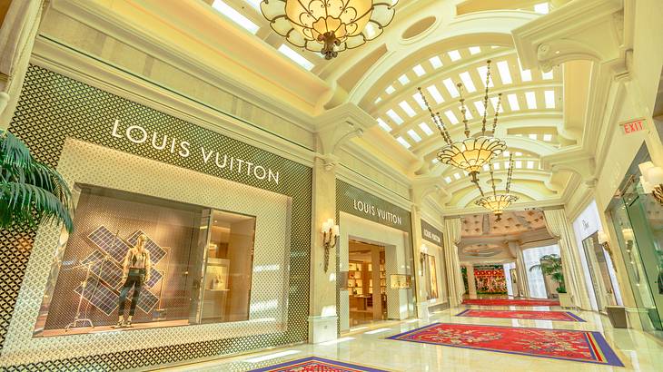 A marble shopping mall with red rugs and a Louis Vuitton store