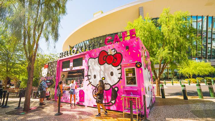 People ordering from a pink food truck with a Hello Kitty image on it