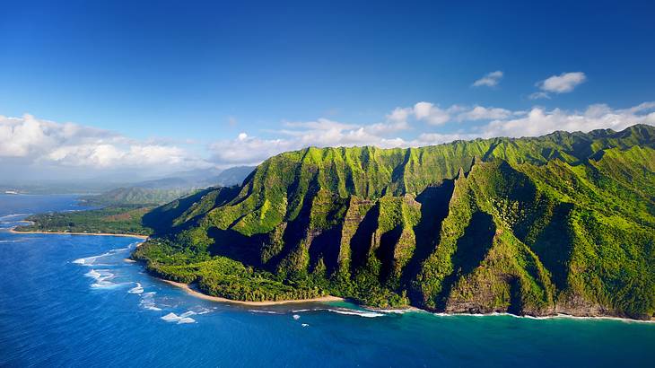 Aerial view of a coastline with a green mountain on the right-hand side