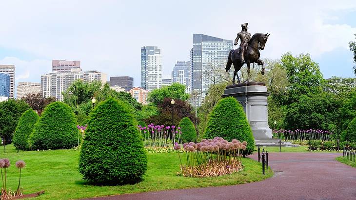 A statue of a man on a horse with a path and green garden surrounding it A statue of a man on a horse with a path and green garden surrounding it