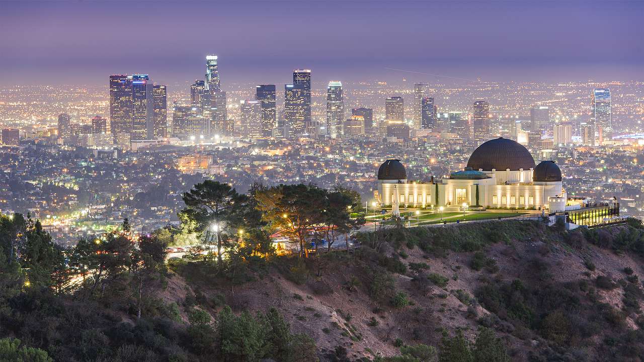 A park and observatory on top of a mountain with a night cityscape at the back