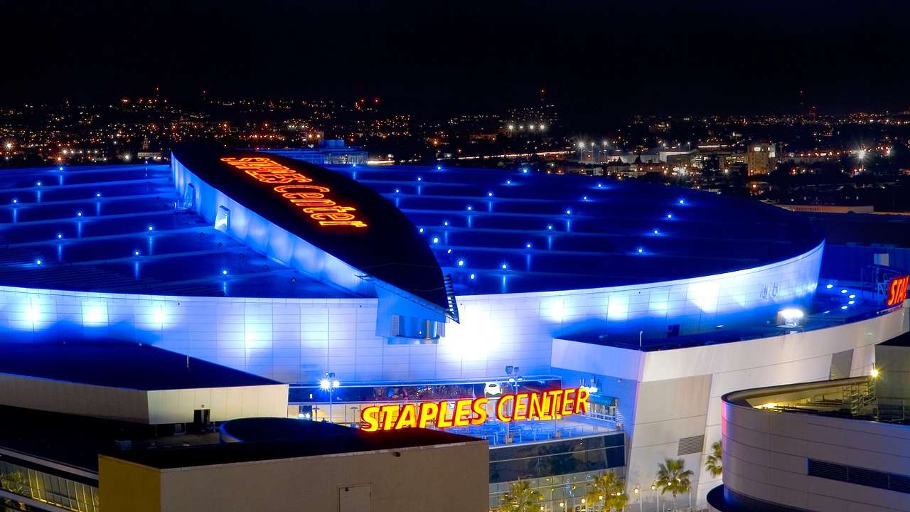 Arena illuminated in blue lights with red neon signage that says Staples Center