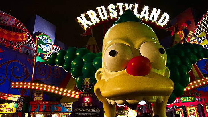 A huge clown head figure with a lit-up Krustyland sign over it