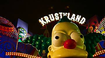 A huge clown head figure with a lit-up Krustyland sign over it