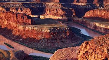Amazing red rock canyon surrounded by a river during sunset