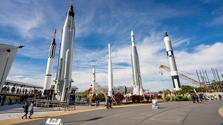 People wandering around a site with six space shuttles on a sunny day People wandering around a site with six space shuttles on a sunny day