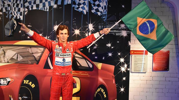 A wax figure of a Formula One driver carrying a green, yellow, and blue flag