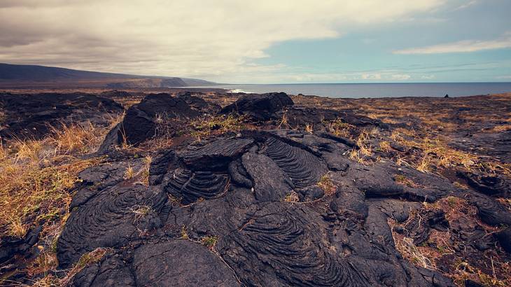 Looking down at layers of cooled lava on a brown grassy hilltop