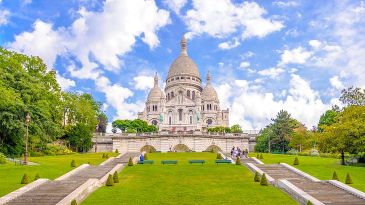 Stairs leading to a white basilica atop a hill surrounded by greenery Stairs leading to a white basilica atop a hill surrounded by greenery