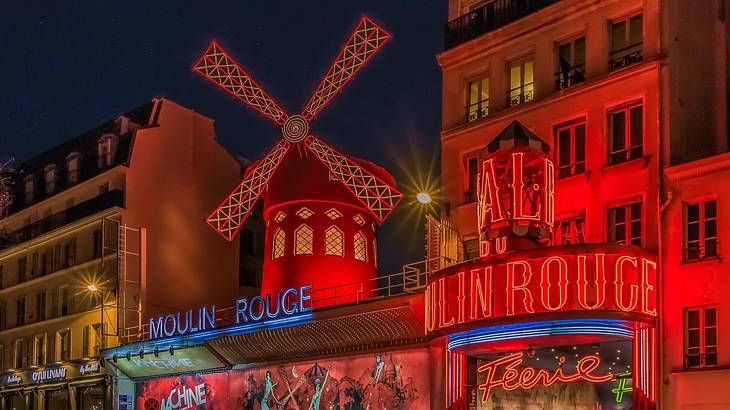 Red Illuminated windmill replica and Moulin Rouge sign at the façade at night