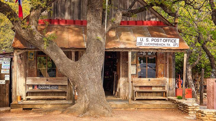 Wood structure with "US Post Office, Luckenbach Texas" signage, under a big tree