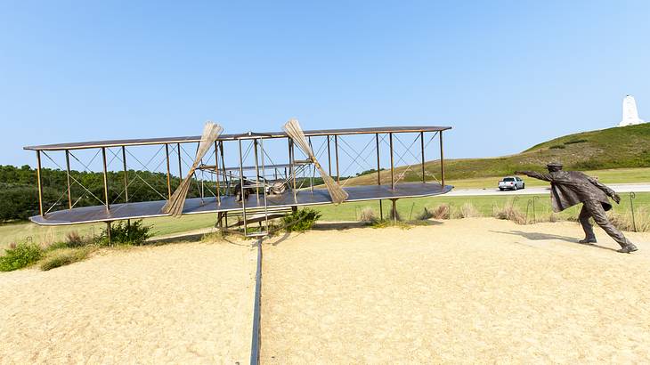 An old-fashioned plane replica with a statue of a person beside it