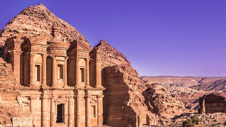 A pink sandstone building carved out of rock in a desert
