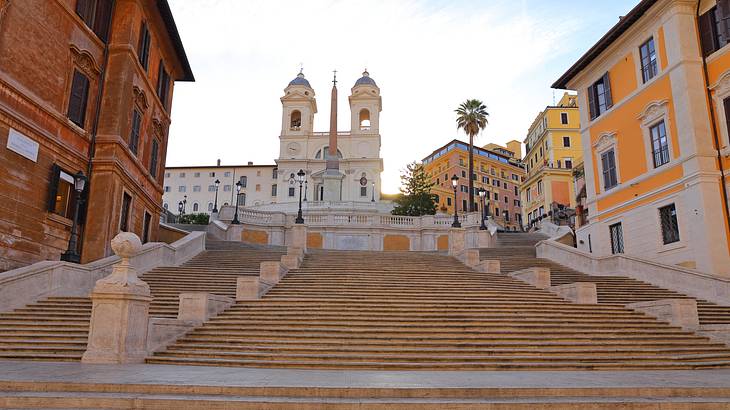 Stairway surrounded by brightly coloured buildings leading to an obelisk and a church