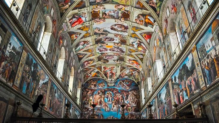 The interior of a chapel with its altar, ceiling, and walls covered in frescoes The interior of a chapel with its altar, ceiling, and walls covered in frescoes