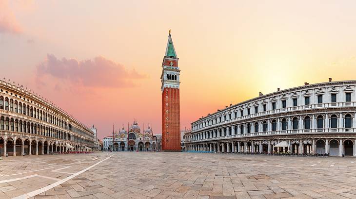 Sunset over an empty plaza with a tower in the middle and buildings on the sides