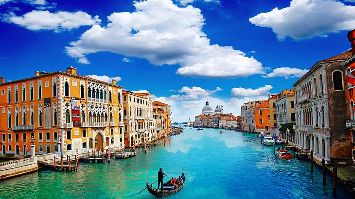 Gondola rides through a canal with turquoise water and buildings on both sides