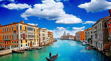 Gondola rides through a canal with turquoise water and buildings on both sides
