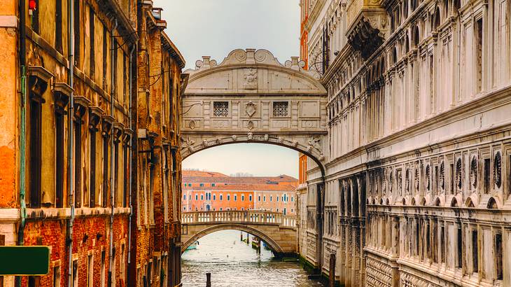 An enclosed limestone bridge spans a narrow canal and connects two buildings