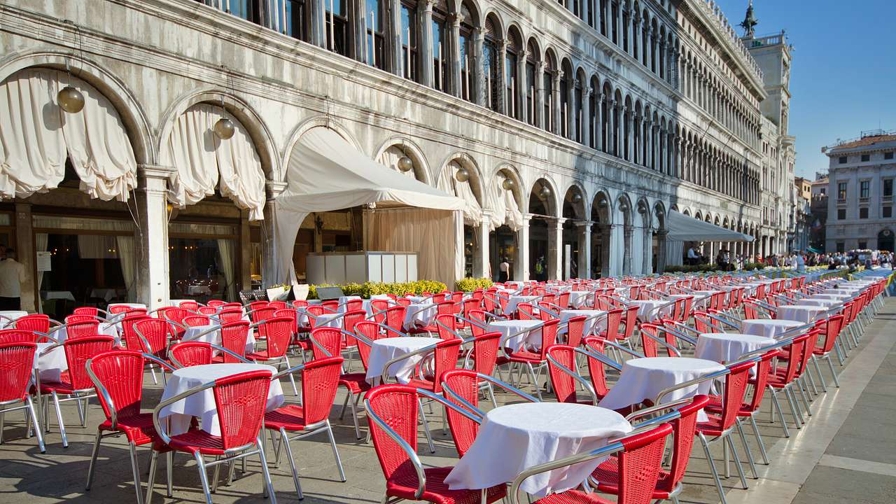 White tables and red chairs al fresco in a square on a sunny day