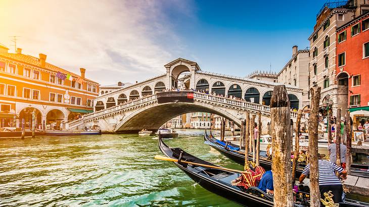 Gondolas parked on canal water on one side with a bridge behind