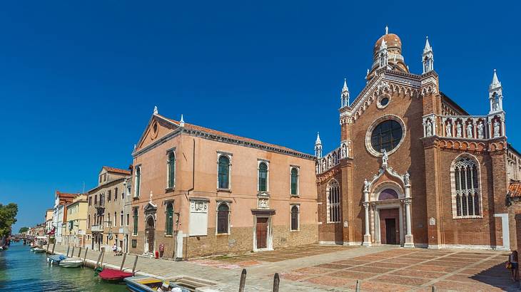 Colorful boats moored in front of a square with a red-brick church