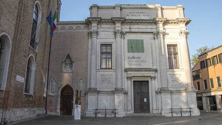 White museum facade with a wooden door in a courtyard