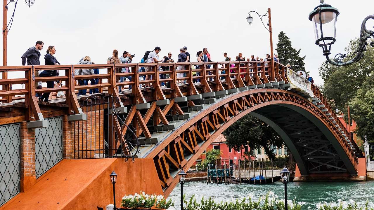 Tourists on a beautiful red wooden bridge crossing a canal