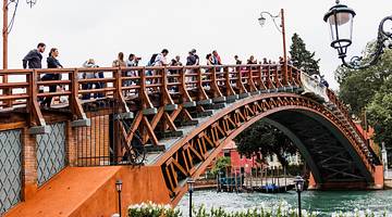 Tourists on a beautiful red wooden bridge crossing a canal