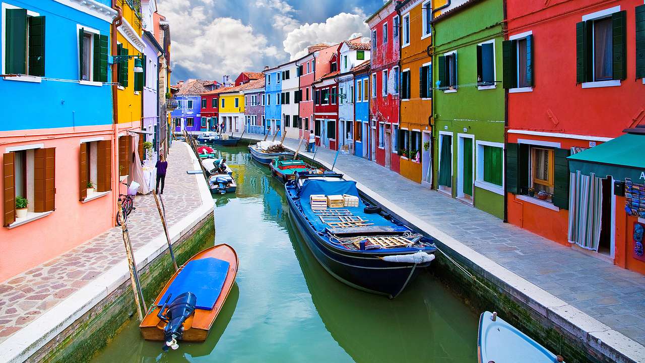 Boats docked at a canal lined by colorful buildings on both sides