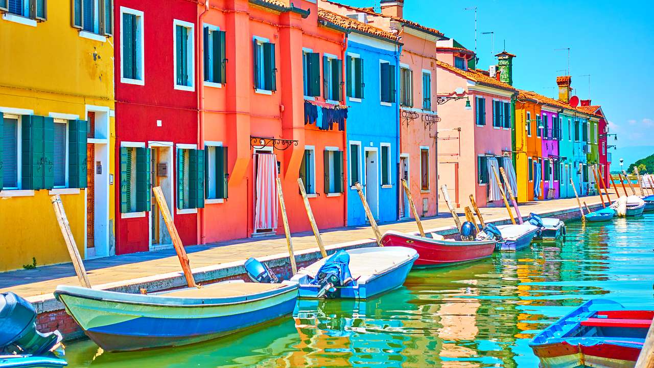 Small boats parked along a boardwalk in front of brightly colored houses