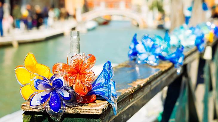 Up-close shot of beautiful colored glass flowers on a wooden balcony