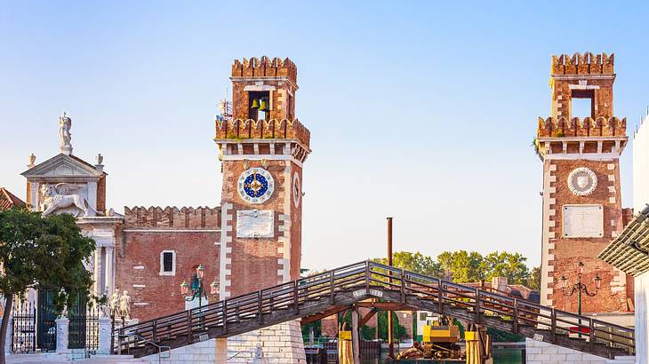 A bridge in front of two red brick towers in the background