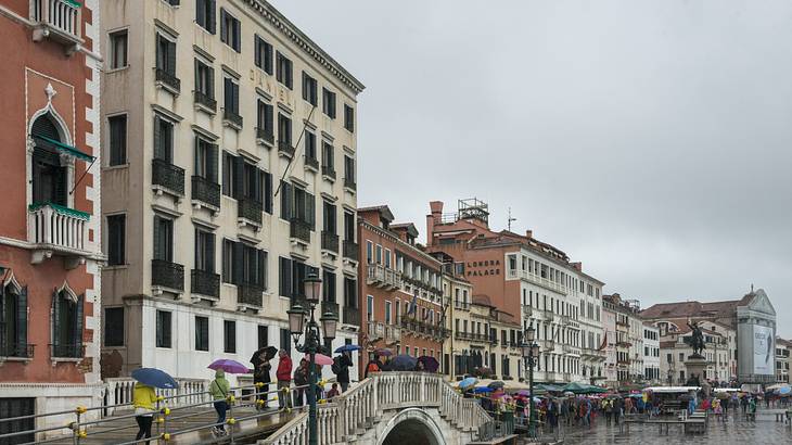 People on a waterfront with buildings on one side on a rainy day