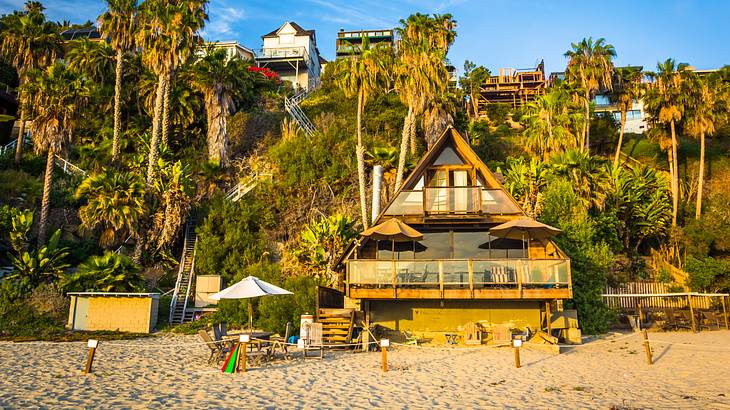A-frame beach house and cliff with palm trees under a blue sky