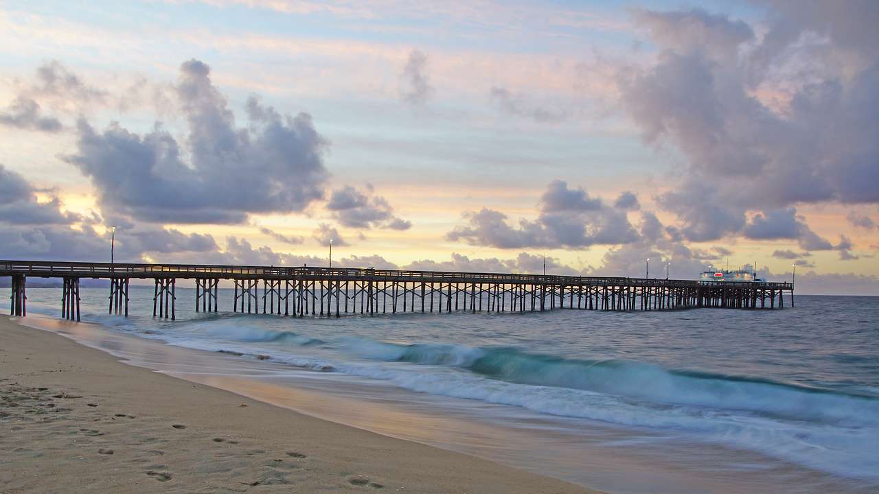 Long wooden over water and a sandy beach at sunrise