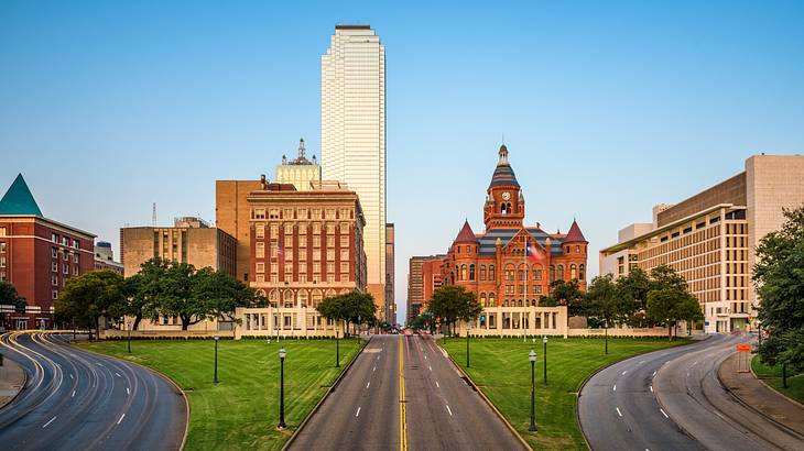 Across a grassy area with three roads, there are historic buildings and a skyscraper