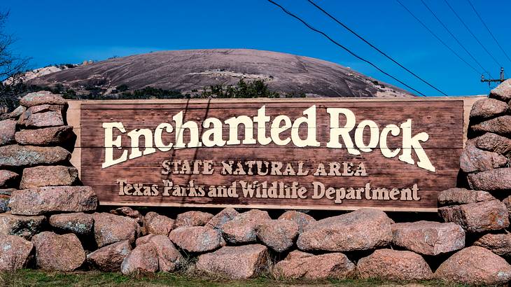 "Enchanted Rock" entry sign made of stones with blue sky in the background