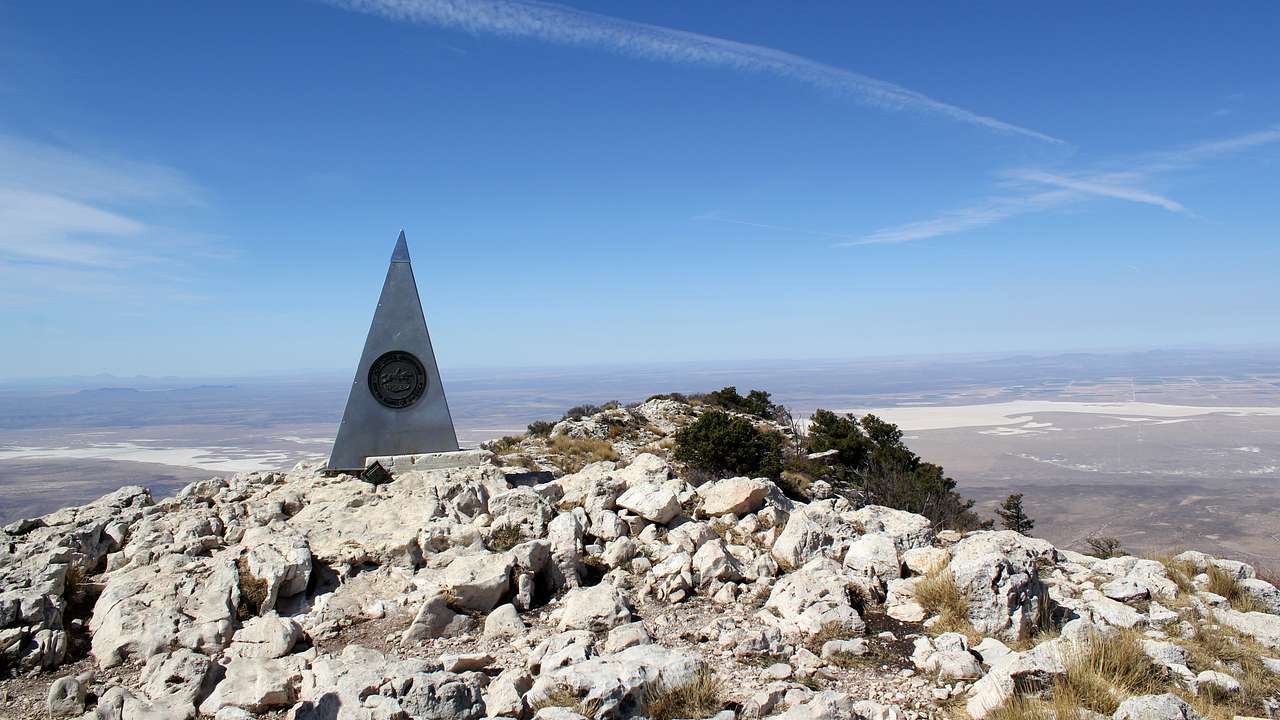 A rocky summit monument with a compass rose, overlooking a desert