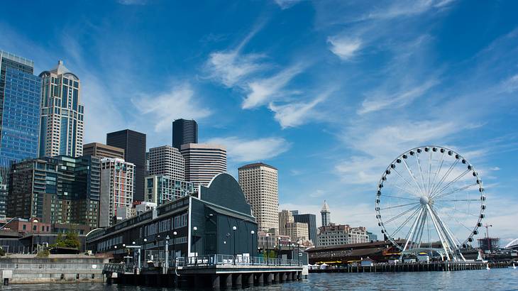 A body of water and a skyline with a Ferris Wheel under a blue sky A body of water and a skyline with a Ferris Wheel under a blue sky