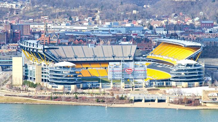 A football stadium with yellow seats with water in front of it A football stadium with yellow seats with water in front of it