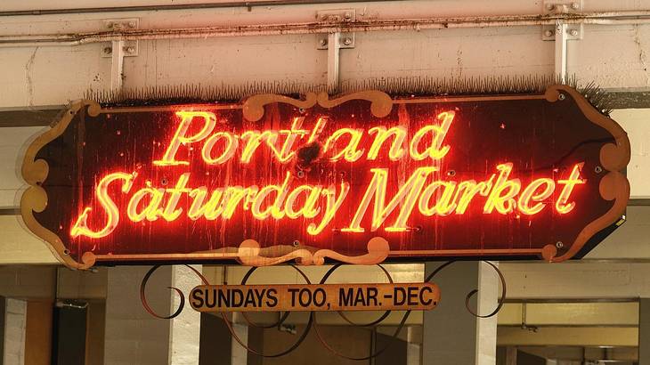 A sign that says "Portland Saturday Market" in red neon letters