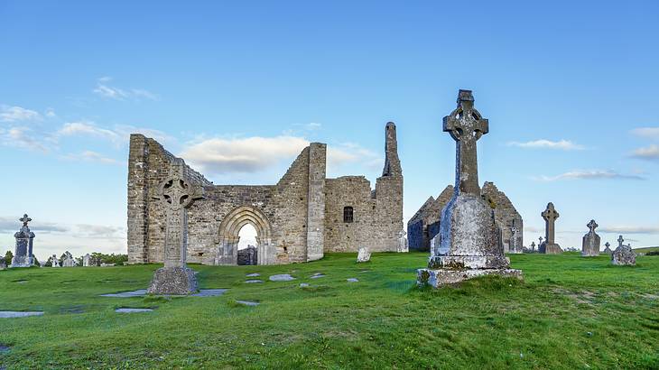 Grave slabs and cathedral ruins on a grassy field with blue sky at the back
