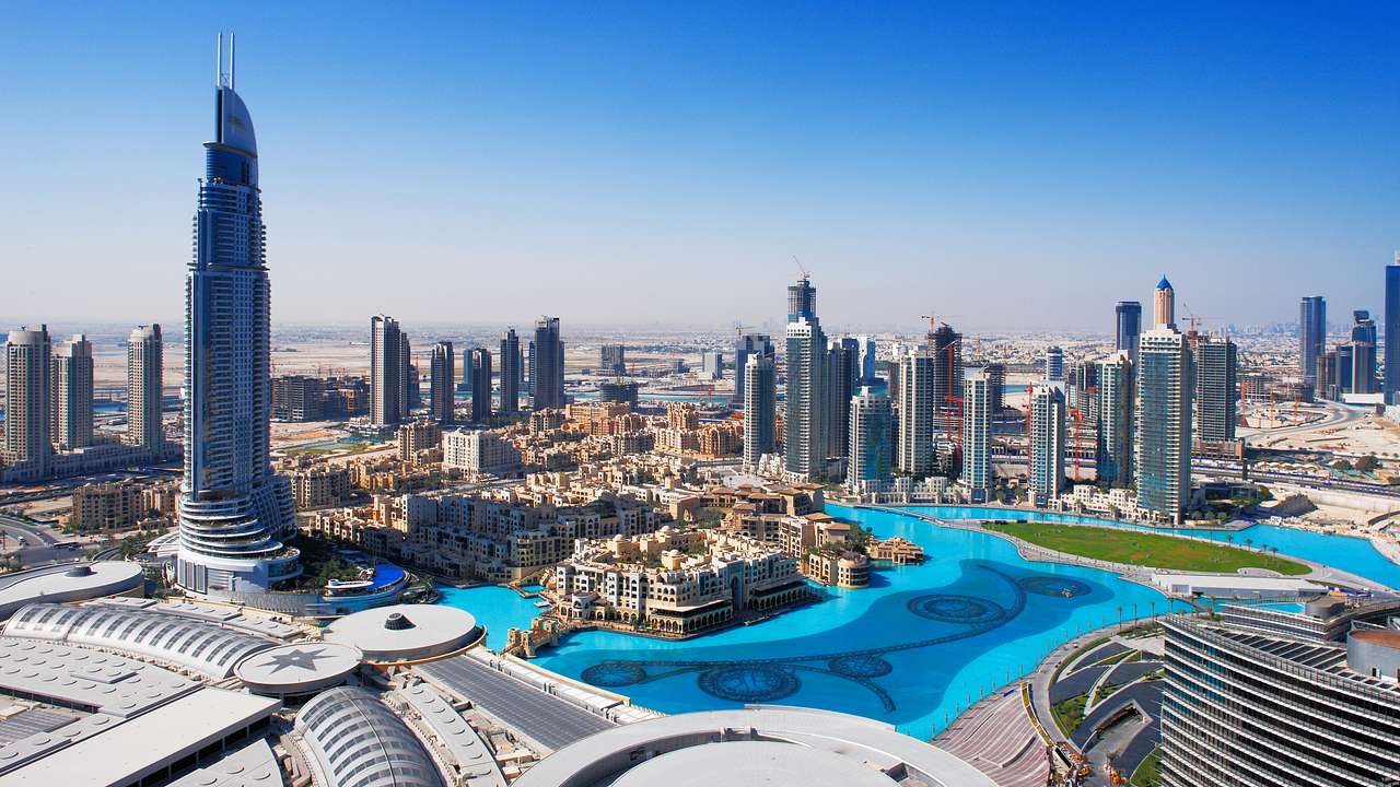 Aerial view of skyscrapers and buildings around a blue body of water under blue skies
