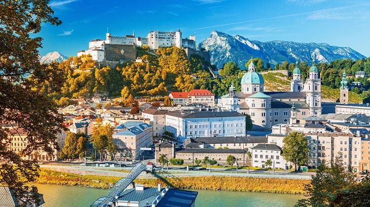 A large white fortress on a hill with a well-preserved city along a river below